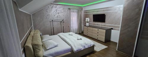 a bedroom with a bed with a green lighting at Casa Perla Nordului in Moisei