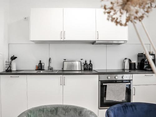 a kitchen with white cabinets and a stove top oven at LIGHTPLACE • Moderne Innenstadt-Wohnung • Balkon zur Oker in Braunschweig