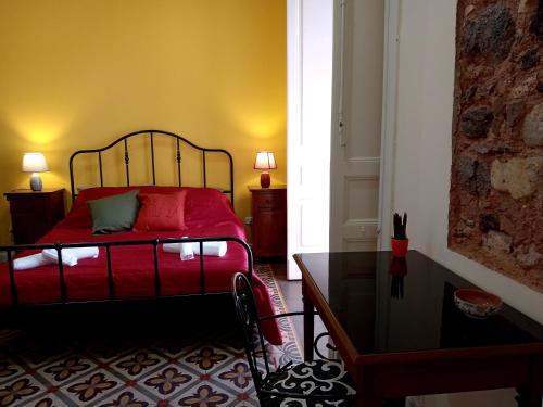 a bedroom with a red bed and a table at Medinat House in Catania