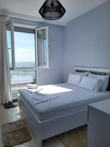 a white bedroom with a large bed and a window at Alex's Apartment 2 in Durrës