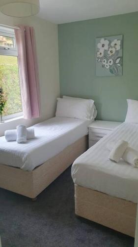 2 camas en una habitación pequeña con ventana en Honicombe Valley Lodge 23 Hot Tub Lodge, en Gunnislake
