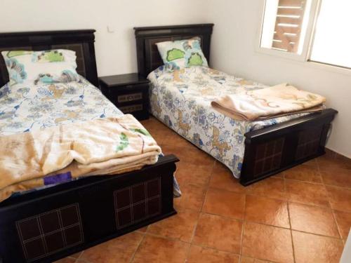 two beds sitting next to each other in a bedroom at Appartement Cassia situé à Cabo Negro in Tétouan