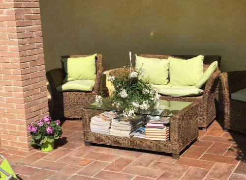 a patio with two wicker chairs and a table with books at Casetta Valderoa Fiumicino in Fiumicino