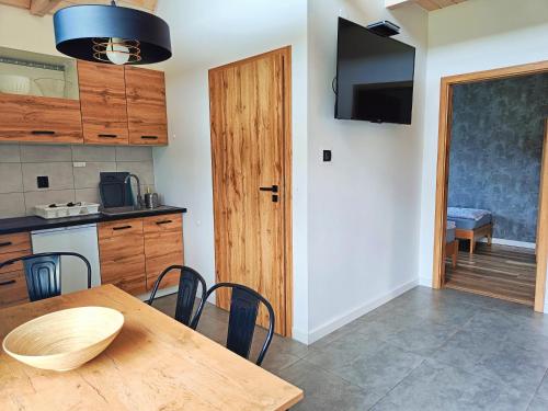 a kitchen with a wooden table and a dining room at Domki Dolina Roztocza in Zwierzyniec