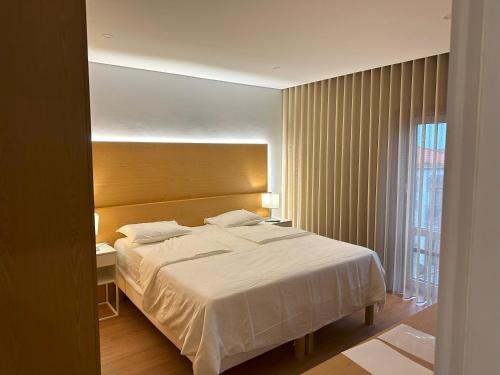a bedroom with a large white bed and a window at Francisco Barbosa in Estarreja