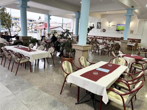 a restaurant with tables and chairs with people in the background at Restaurant & Apartments JUG in Sutomore