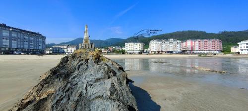 uma grande rocha na areia numa praia em Alojamientos Viveiro - Ático Playa de Covas em Viveiro