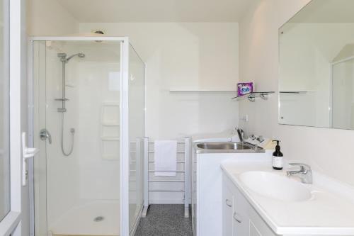 a white bathroom with a shower and a sink at Kereru Rest in Rotorua