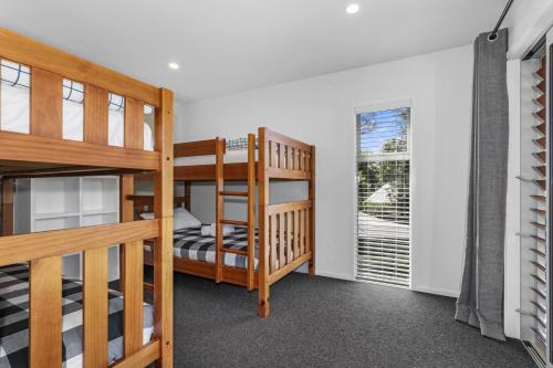 two bunk beds in a room with a window at Kereru Rest in Rotorua