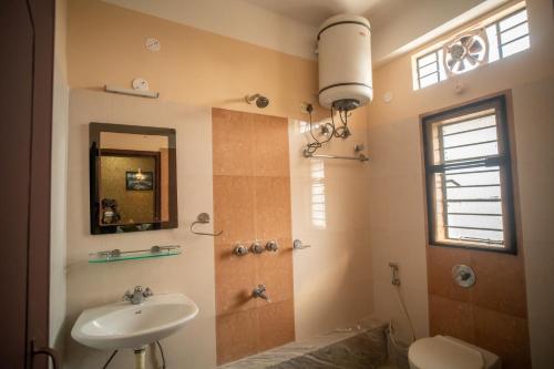 a bathroom with a sink and a toilet and a mirror at Siliguri Club in Siliguri