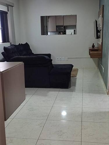 a living room with a black couch and a tile floor at Apartamento Park 1 in Dourados