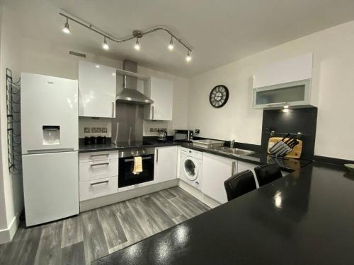uma cozinha com armários brancos e um balcão preto em Luxury Apartment with Balcony em Dewsbury