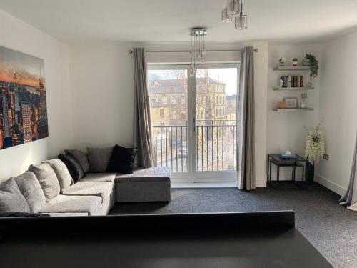 a living room with a couch and a large window at Luxury Apartment with Balcony in Dewsbury