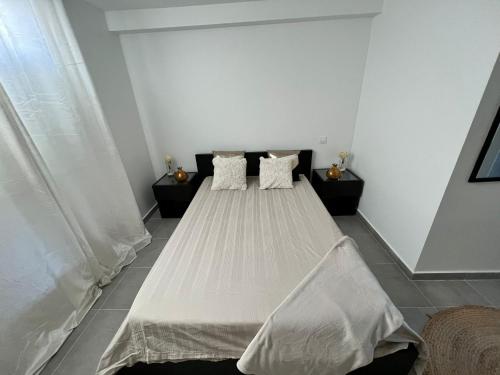 Schlafzimmer mit einem Bett mit weißer Bettwäsche und Kissen in der Unterkunft Appartement en rez-de-jardin in Vitry-sur-Seine