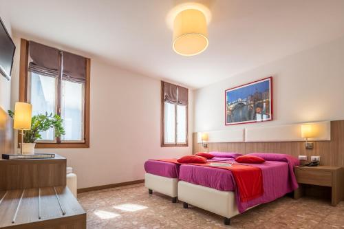 a bedroom with a large bed with a purple blanket at Hotel Il Moro di Venezia in Venice