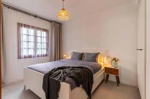 a white bedroom with a large bed and a window at Casa Narnia in Puerto del Carmen