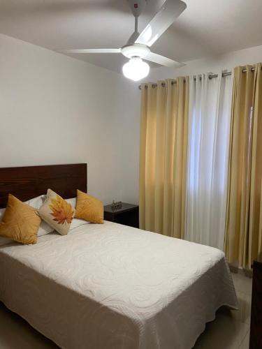 Schlafzimmer mit einem weißen Bett und einem Deckenventilator in der Unterkunft My Beautiful Place in Santiago de los Caballeros