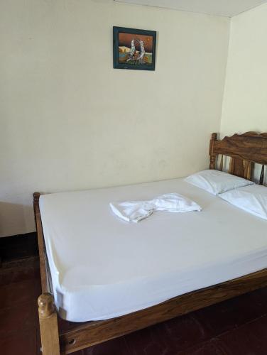 a bed with white sheets and a picture on the wall at Hotel Playa Santa Martha in Rivas