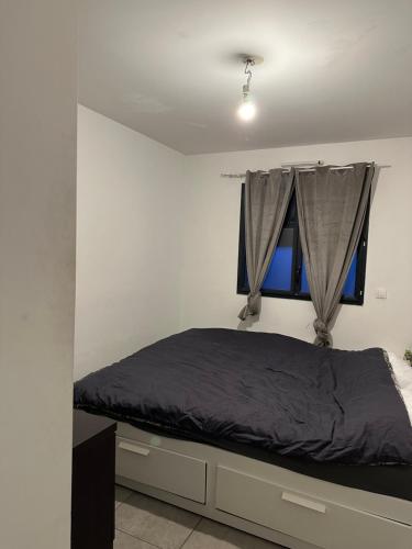- une chambre avec un lit doté de draps gris et une fenêtre dans l'établissement L'appartement, à Tremblay-en-France