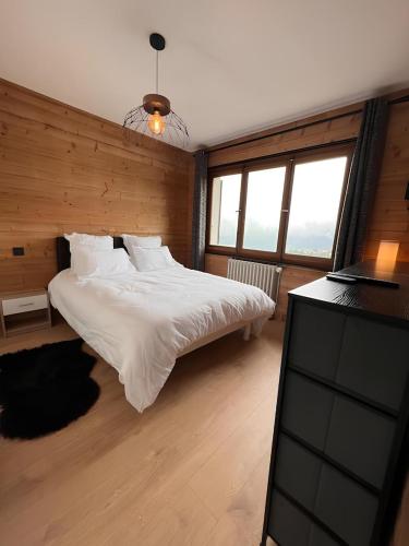 une chambre avec un lit blanc et une télévision dans l'établissement Vue Mont blanc, ski et village, à Combloux
