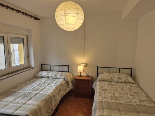 1 dormitorio con 2 camas y lámpara. en Rodastur, en Pravia