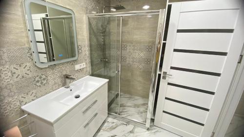 a bathroom with a shower and a sink and a mirror at Apartament in Bălţi