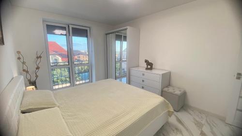 a white bedroom with a bed and two windows at Apartament in Bălţi
