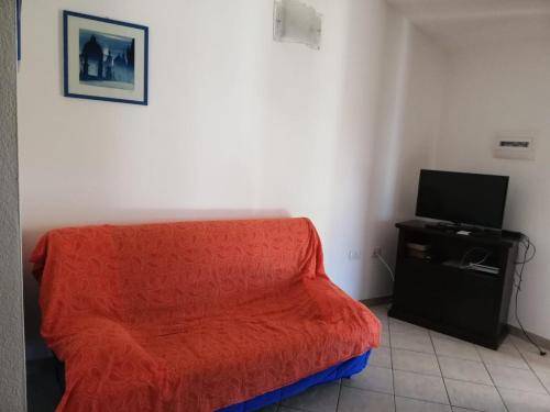 una camera con una coperta rossa e una TV di Casa Solaria Villetta singola panoramicissima a Costa Rei