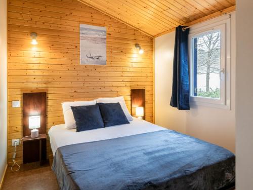 ein Schlafzimmer mit einem Bett mit einer Holzwand in der Unterkunft Cottage 5 personnes Bias Mimizan in Bias