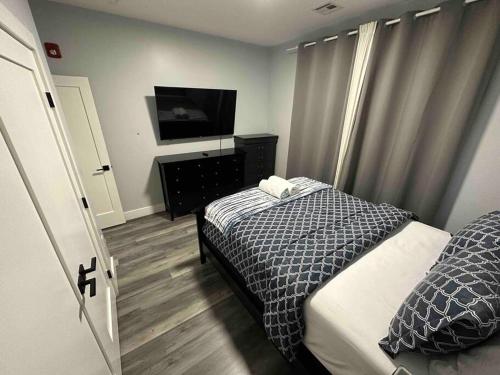 Schlafzimmer mit einem Bett und einem Flachbild-TV in der Unterkunft The Stylish Suite - 1BR with Free Parking in Paterson