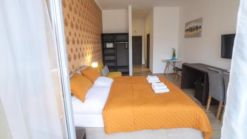 a bedroom with a large bed with an orange blanket at Premium City Centre Bedrooms in Prešov