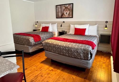 Habitación de hotel con 2 camas con almohadas rojas en Aux Portes du Soleil, en Baie-Saint-Paul