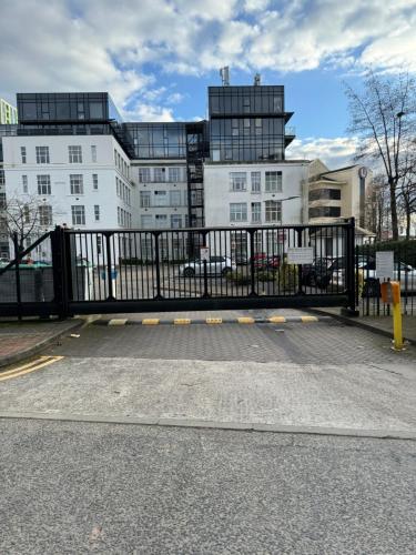 a black gate in a parking lot with buildings at Stunning Salford Quays Apartment in Manchester