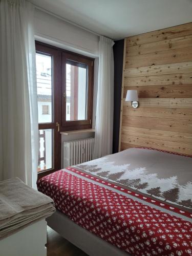 a bedroom with a red and white bed with a window at Condominio Le Grange - Casa E in Sauze dʼOulx