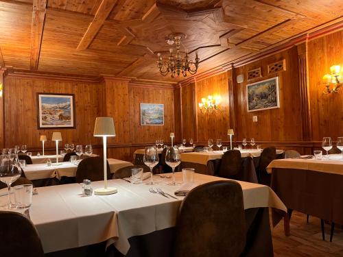 a dining room with tables and chairs and a chandelier at Hotel De Champoluc in Champoluc