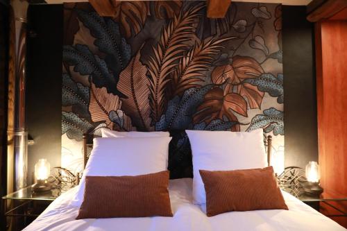 uma cama com 2 almofadas num quarto com um mural de parede em La Petite Maison de Torgny em Torgny