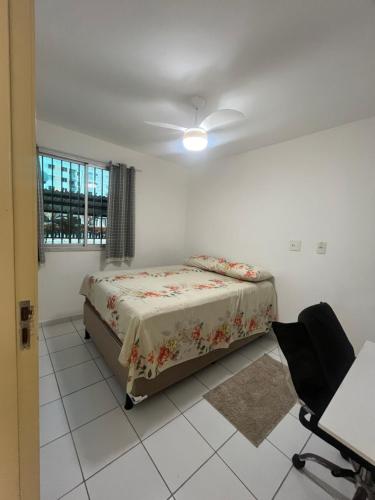 a bedroom with a bed and a chair and a window at Mar de Aruana - Apartamento Suíte com Ar Aracaju-SE in Aracaju