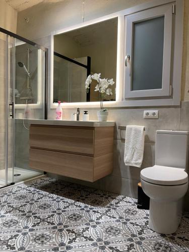 a bathroom with a sink and a toilet and a mirror at Cal Querol - Puigcerdà centre in Puigcerdà