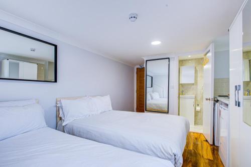 two beds in a small room with white walls at Streatley Apartments in London