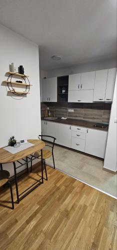 une cuisine avec des placards blancs et une table en bois dans l'établissement DM apartman Divcibare, à Divčibare
