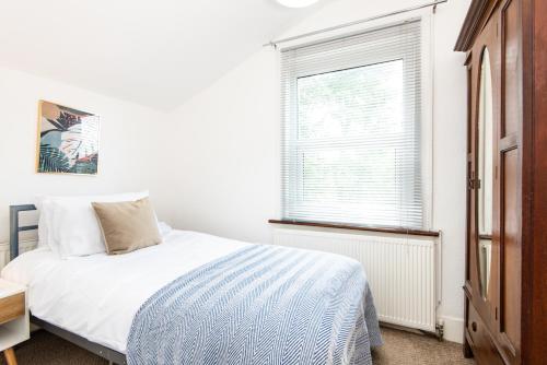 a white bedroom with a bed and a window at Single Room with a shared Kitchen and bathroom in a 5-Bedroom House at Hanwell in Hanwell