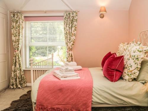 a bedroom with a bed with a red blanket and a window at Charming Country Cottage in Selborne