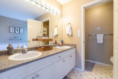 baño con 2 lavabos y espejo grande en Stunning Rustic Vacation home with180-degree Mountain View en Abbotsford