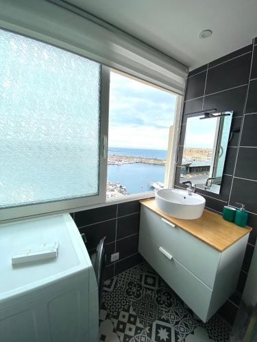 une salle de bain avec un lavabo et une grande fenêtre dans l'établissement Lapromenadesete, à Sète