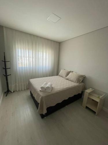a bedroom with a bed with two towels on it at Sobrado com piscina, banheira e garagem coberta. in Piçarras