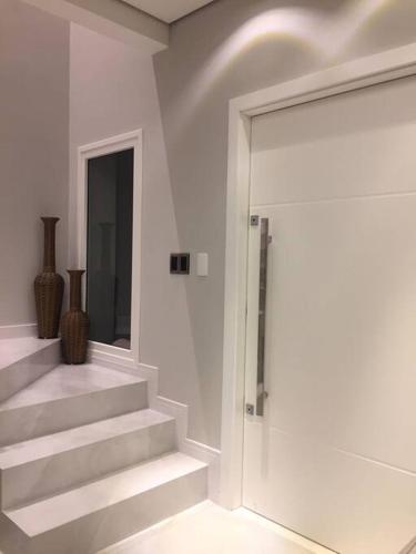 a white room with stairs and a glass door at Sobrado com piscina, banheira e garagem coberta. in Piçarras