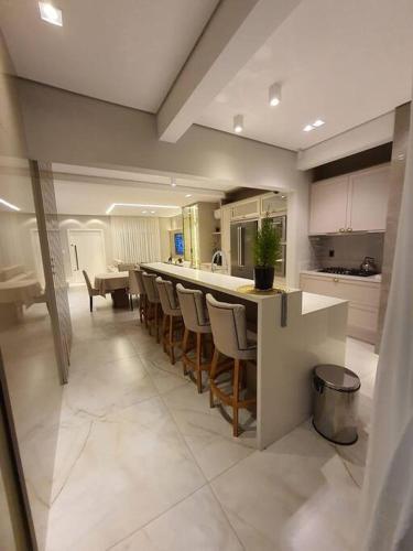 a kitchen with a bar with chairs and a table at Sobrado com piscina, banheira e garagem coberta. in Piçarras