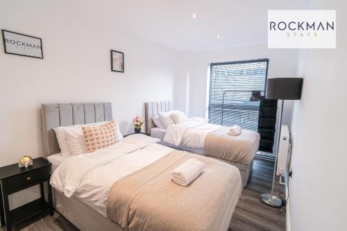 ein Schlafzimmer mit zwei Betten und einem Fenster in der Unterkunft Royal Oak 3 - FREE PARKING - Perfect for Contractors - 2 Bedroom - 2 Bathroom - Fast Wi-fi - Long Term Stays - in Brentwood