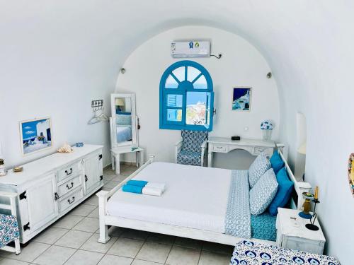 a bedroom with a bed and a dresser and a mirror at Oia Sunset House Pothitou in Oia