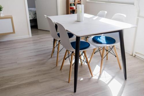 a white table and chairs in a room with wood floors at 5 min Apartment in Banja Luka